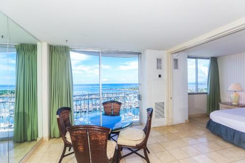a bedroom with a bed and a table and some windows at Ilikai Marina 1584 in Honolulu