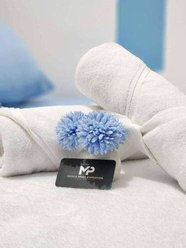 a white towel with a blue flower on a bed at 438 Shore Residences tower B - MOA in Sampong