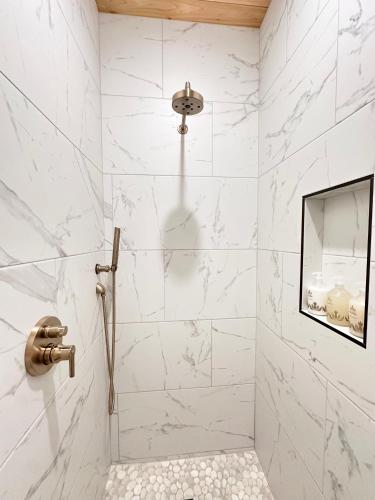 a bathroom with a shower with white marble walls at Sommer House Inn-Aloha Room in Jasper