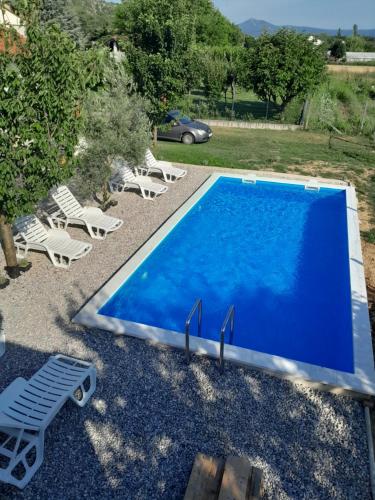 a blue swimming pool with chairs and a yard at Apartman Maga in Čapljina