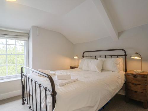 a bedroom with a bed with white sheets and a window at The Nest in Lyme Regis