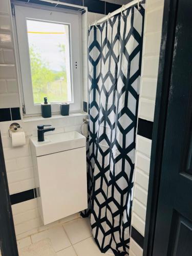 a bathroom with a shower with a sink and a window at Csillagkapu Vendégház in Kápolnásnyék