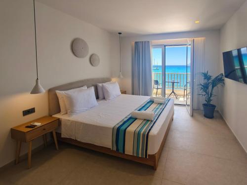 a bedroom with a bed with a view of the ocean at Aeolia Seaside Hotel in Kardamaina