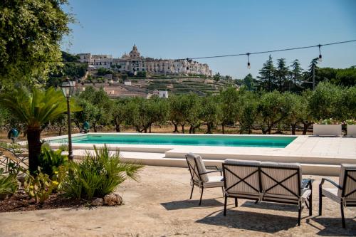 a swimming pool with two chairs and a building at Masseria Trulli Bruni in Locorotondo
