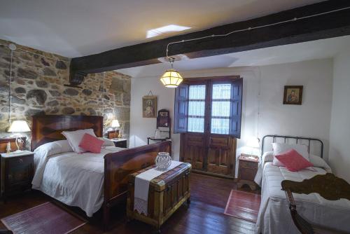 a bedroom with two beds and a stone wall at APARTAMENTO RURAL ABUELO EMILIO in Tornavacas
