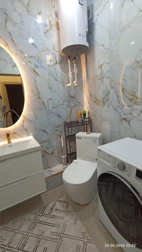 a bathroom with a toilet and a sink and a washing machine at Osh apartment in Osh
