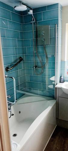 a blue tiled bathroom with a shower and a tub at Comfortable Double Bedroom in Darlington