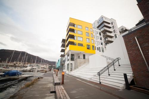 un edificio amarillo al lado de un puerto deportivo en BJØRVIKA APARTMENTS, Damsgård Area, Bergen city center, en Bergen