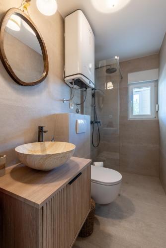 a bathroom with a sink and a toilet and a mirror at Apartments Lučina in Bol