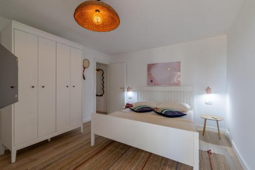 a white bedroom with a bed and a table at Apartments Lučina in Bol