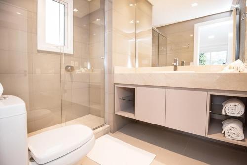 a bathroom with a shower and a toilet and a sink at Hotel Cercano in Gramado