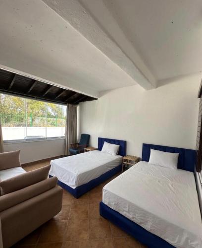 a bedroom with two beds and a couch and a window at Blue Horizon in Cabo Negro