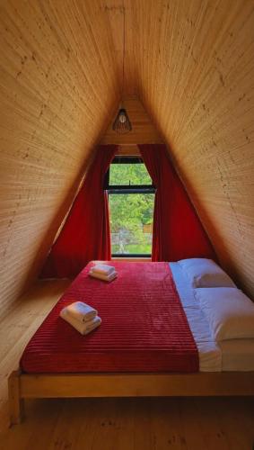 a red bed in a wooden room with a window at Garden Cottages in Mestia