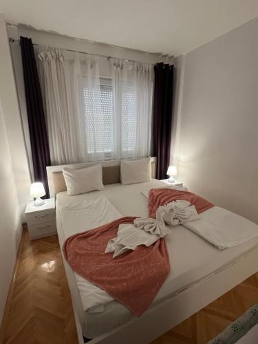 a bedroom with a bed with white sheets and a window at Vista Azul Apartment in Ohrid