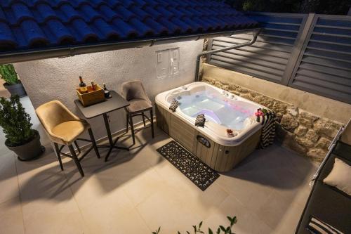 a hot tub on a patio with a table and chairs at Korina Suites - 2 appartments, 1 with jacuzzy in Dramalj
