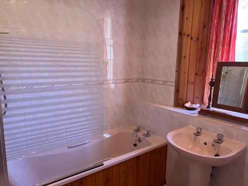 a bathroom with a tub and a sink at Laundry Cottage in Lanark