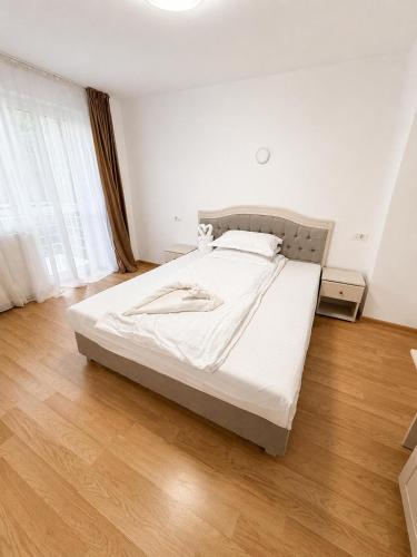 a bedroom with a bed with white sheets and a wooden floor at Balea Events in Cîmpeni