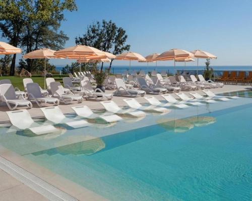 a row of chairs and umbrellas next to a swimming pool at Luxury Sea View Appartment with Beach Access - Parking & Heated Pool in Varna City