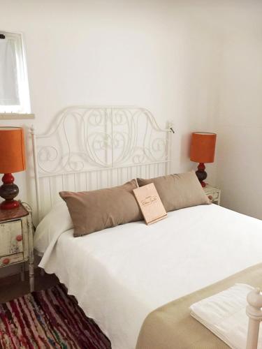 a bedroom with a white bed with a book on it at Herdade Alem Santos in Lousal