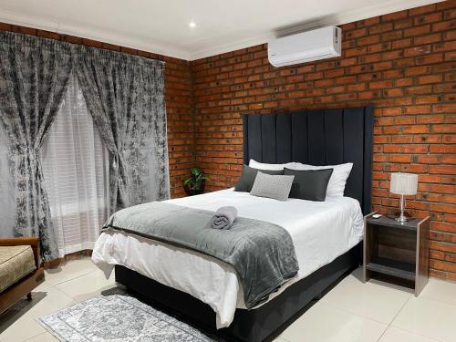 a bedroom with a large bed and a brick wall at Kubbe Comfort Corner in Bloemfontein
