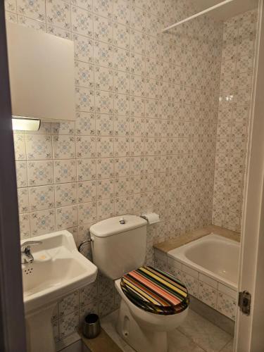 a bathroom with a toilet and a sink and a tub at Casa A Beira do Mar in O Grove