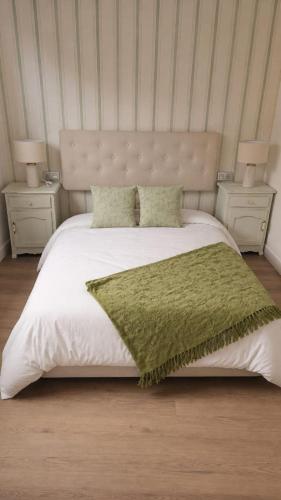 a bed with a green blanket and two night stands at Casa A Beira do Mar in O Grove