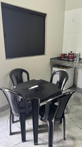 a black table with four chairs and a flat screen tv at Mini flat 08 em Jataí Go in Jataí