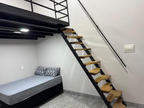 a room with a bed and a spiral staircase at Mini Flat 09 Jataí Go in Jataí