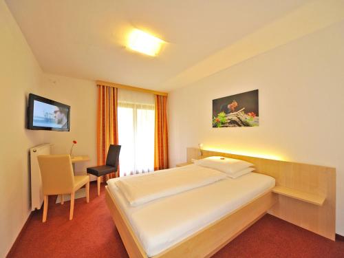 a hotel room with a bed and a table and a chair at Pension Isabella in Bad Kleinkirchheim