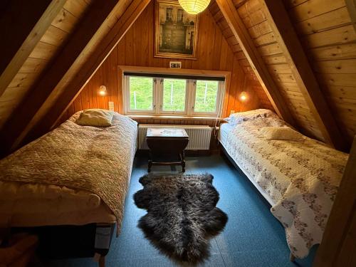 a attic bedroom with two beds and a rug on the floor at Unique and isolated cottage with stunning views in Leynar