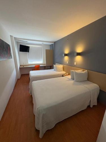 a hotel room with three beds and a window at One Irapuato in Irapuato