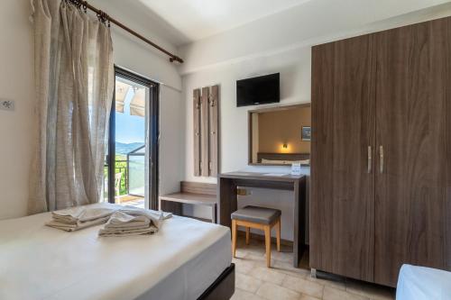 a bedroom with a bed and a desk and a window at Studios Vaso in Neos Marmaras