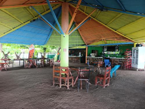 a restaurant with tables and chairs under a large roof at Kencho's Beach House-Sunset & Beachside stay in Ometepe in El Perú