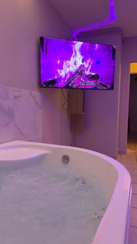 a bathroom with a bath tub with a tv on the wall at Romantic Suite with Private Jacuzzi in Noyon