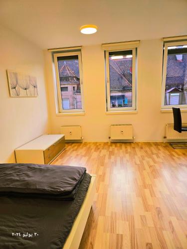 a room with a bed and windows and a wooden floor at Nürnberg Nähe Studio in Fürth