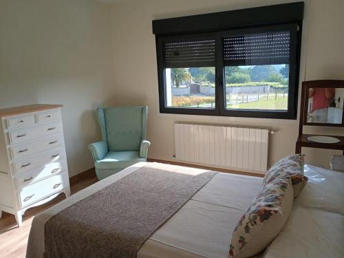a bedroom with a bed and a chair and a window at A de Amancio in Sayáns