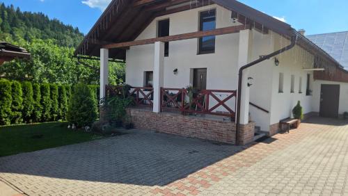 a white house with a red gate and a brick driveway at Ubytovanie u Adama in Oščadnica