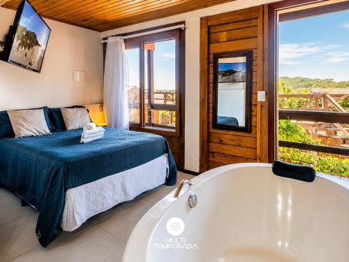 a bedroom with a bed and a bath tub at Pousada Solar dos Lírios - Praia do Rosa in Praia do Rosa