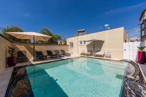 a swimming pool with chairs and an umbrella at Oasis Paradise Pool Villa in Durrës