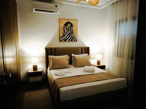a bedroom with a bed with two lamps and a painting on the wall at Palm Paradise in Sukrah