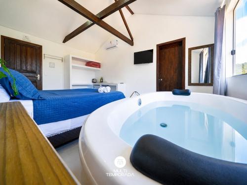 a bathroom with a tub in a bedroom with a bed at Pousada Solar dos Lírios - Praia do Rosa in Praia do Rosa