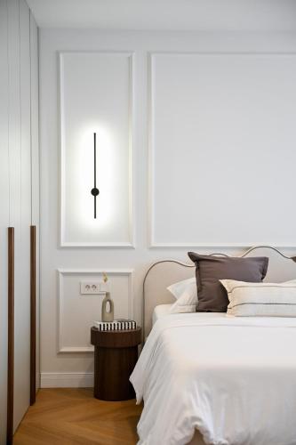 a white bedroom with a bed and a clock on the wall at Casa Magista in Sukošan