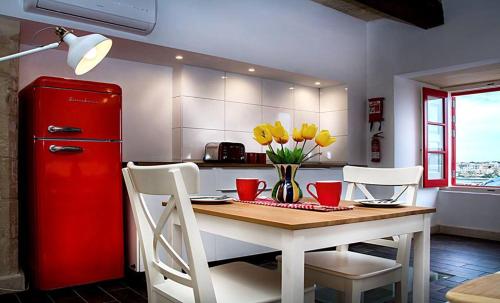 eine Küche mit einem roten Kühlschrank und einem Tisch mit gelben Blumen in der Unterkunft Luciano Valletta Studio - Self Catering in Valletta