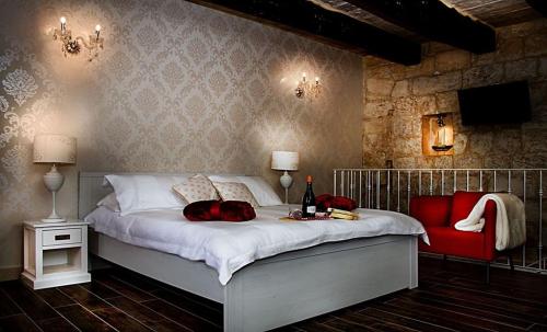 1 dormitorio con 1 cama grande y 1 silla roja en Luciano Valletta Studio - Self Catering, en La Valeta