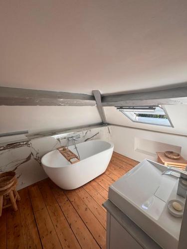 a bathroom with a white bath tub on a wooden floor at La maison de Blandine in Honfleur