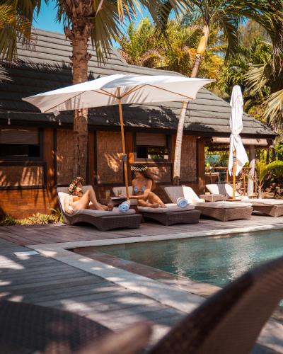 a group of people laying on lounge chairs by a pool at Green Lodge Moorea in Teavaro