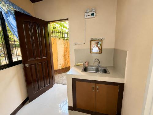 a small kitchen with a sink and a door at Argana Cottages in Dauin