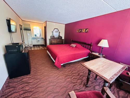 a bedroom with a red bed and a table at Colonial Mountain Inn Branson MO in Branson West