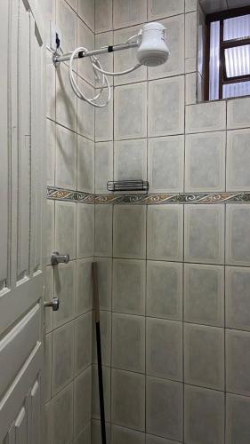 a bathroom with a tiled wall with a mop at Central APE Diamantina in Diamantina