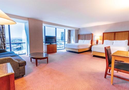 a hotel room with two beds and a couch at Masquerade Tower at Rio Hotel & Casino in Las Vegas